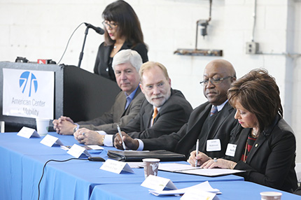 WCC President Dr. Rose B. Bellanca (right) signs the Academic Consortium agreement at the American Center for Mobility on Monday as (from left) Governor Rick Snyder, Oakland University VP David Stone and Wayne County Community College District Provost James Robinson look on.