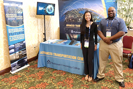 WCC students Rosa Lechartier and Zachyre Van Buren stand at the college's exhibit during the Center for Automotive Research Management Briefing Seminars in Traverse City.
