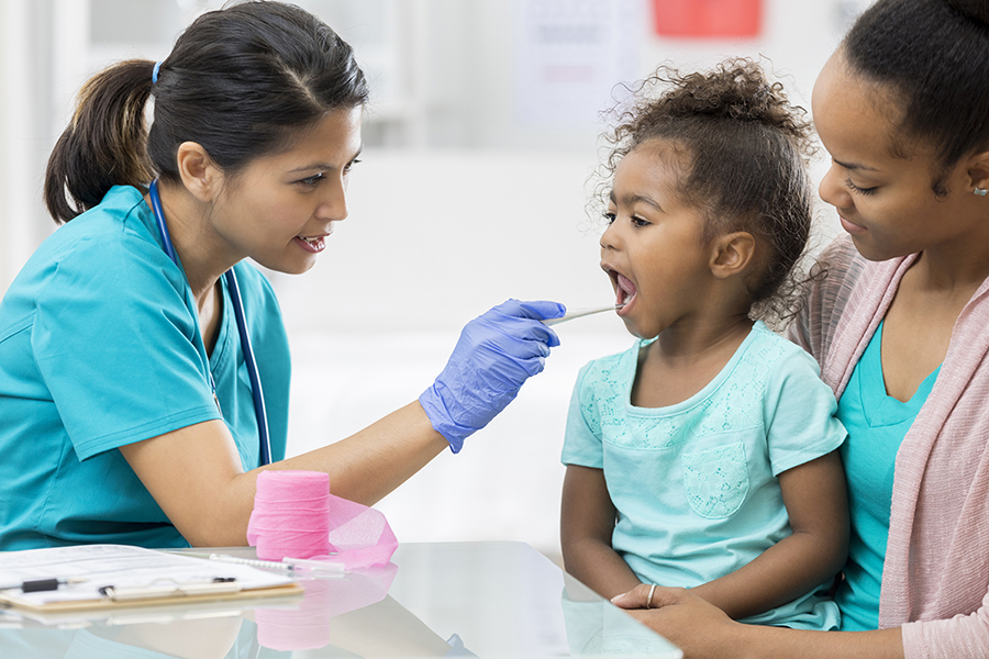 Medical Assistant checking young girl's throat